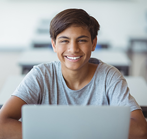 smiling boy at desk with laptop
